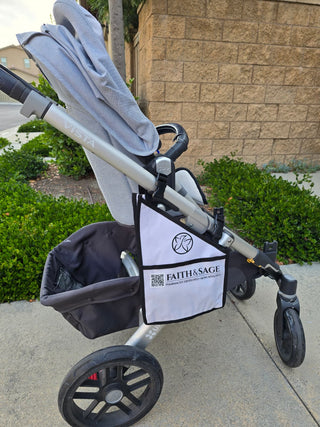 Stroller with a Faith & Sage bag attached on a sidewalk.